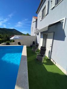 a yard with chairs and a swimming pool next to a house at Casa Bellavista in Nerezine