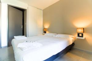 sypialnia z dużym białym łóżkiem z ręcznikami w obiekcie SELECT'soHOME - Résidence Le Levant - Services hôteliers - Appartement proche plage&commerces avec parking ! - LEV41 w mieście Le Lavandou