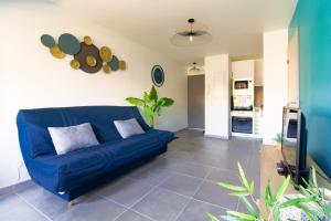 niebieską kanapę w salonie z kuchnią w obiekcie SELECT'soHOME - Résidence Le Levant - Services hôteliers - Appartement proche plage&commerces avec parking ! - LEV41 w mieście Le Lavandou +6 zdjęć