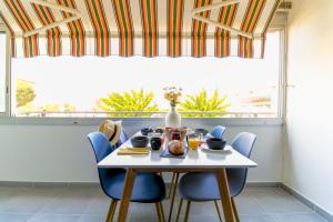 Biały stół z niebieskimi krzesłami i oknem w obiekcie SELECT'soHOME - Résidence Le Levant - Services hôteliers - Appartement proche plage&commerces avec parking ! - LEV41 w mieście Le Lavandou