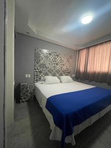 a bedroom with a large bed with a blue blanket at Hotel Rias in Veracruz