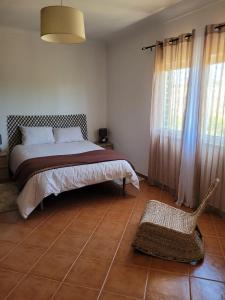 a bedroom with a bed and a chair in it at Quinta dos Moledros in Figueira
