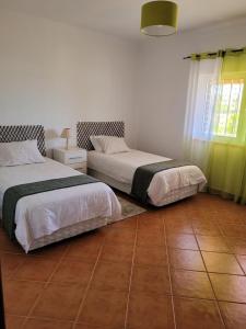 a bedroom with two beds and a tile floor at Quinta dos Moledros in Figueira