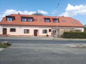 a white house with a red roof on a street at Penzion U Hladů in Úlice