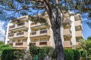 un immeuble d'appartements avec un arbre devant dans l'établissement Chic Appart du Port Fréjus, à Fréjus
