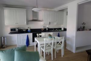 a kitchen with white cabinets and a table and chairs at Spacious 70 m flat with Balcony and sea view! in Cannes