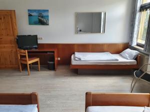 a room with two beds and a desk and a television at Stay2Night Hotel in Dillingen an der Saar