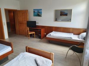 a room with two beds and a desk with a television at Stay2Night Hotel in Dillingen an der Saar