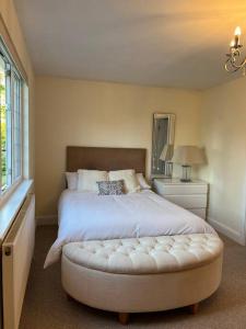 a bedroom with a large white bed with a ottoman at Self contained, spacious annex with private drive. in Kent