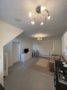 a living room with a couch and a chandelier at Self contained, spacious annex with private drive. in Kent +16 photos