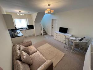 a living room with a couch and a table and a kitchen at Self contained, spacious annex with private drive. in Kent