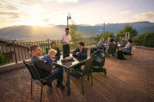 un gruppo di persone seduti intorno a un tavolo su un patio di La Montanina Hotel in Val di Non a Malosco