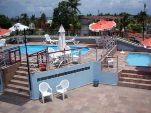 a swimming pool with chairs and umbrellas next to a pool at Pousada Recifes de Corais in Porto De Galinhas