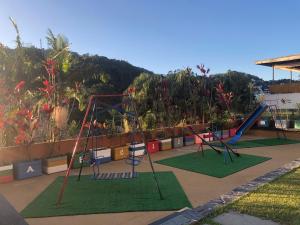 three swings in a playground with a hill in the background at Casa do Sol Hotel in Petrópolis