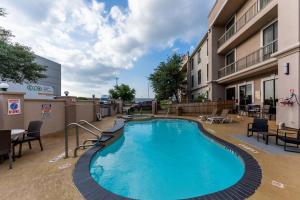 a swimming pool with chairs and a table and a building at Comfort Suites Houston West at Clay Road in Houston