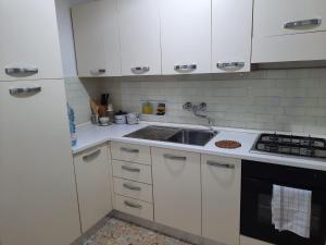 a kitchen with white cabinets and a sink at PORTA A MARE STATION in Pisa