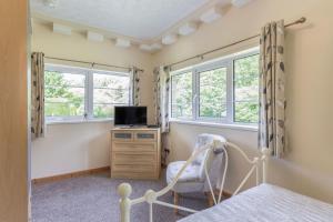 um quarto com uma cama, uma cadeira e janelas em Jarrah em Marwood
