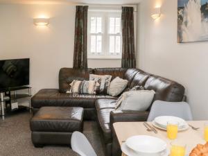 a living room with a leather couch and a table at Razorbill Cottage in Whitby
