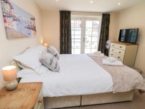 a bedroom with a large white bed and a television at Razorbill Cottage in Whitby