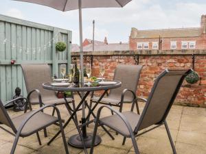 a table with chairs and an umbrella on a patio at Razorbill Cottage in Whitby