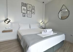 a white bedroom with a large bed with a mirror at Feel Athens Studios at Monastiraki in Athens
