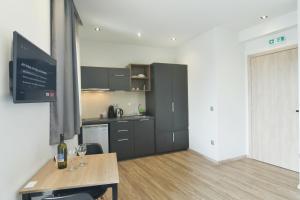 a kitchen with black cabinets and a table with wine glasses at Feel Athens Studios at Monastiraki in Athens