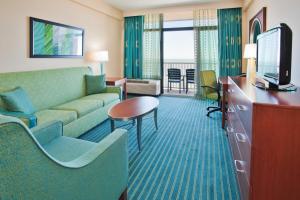um quarto de hotel com um sofá e uma televisão em Holiday Inn & Suites Virginia Beach - North Beach, an IHG Hotel em Virginia Beach