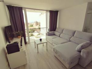 a living room with a couch and a large window at BRISAMAR Apartamento con aire acondicionado in Torremolinos