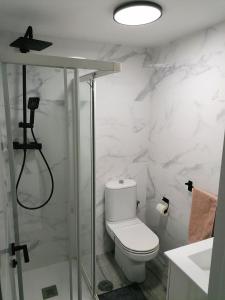 a white bathroom with a toilet and a shower at BRISAMAR Apartamento con aire acondicionado in Torremolinos