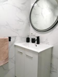 a white bathroom with a sink and a mirror at BRISAMAR Apartamento con aire acondicionado in Torremolinos