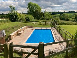ein Pool in einem Garten mit einem Zaun in der Unterkunft The Shepherd's Hut with cozy logburner in Wrexham