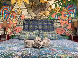 - un lit en face d'un mur orné d'une fresque murale dans l'établissement Majikal B&B - Pueblo Maya, à Mérida