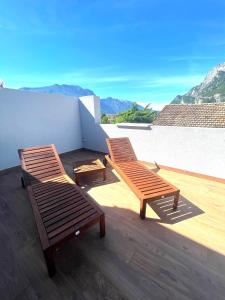 dwa drewniane krzesła siedzące na balkonie z górami w obiekcie Garda Family & Solarium w mieście Riva del Garda