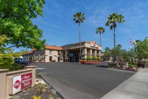 a view of the front of a hotel with palm trees at Best Western Plus Hilltop Inn in Redding
