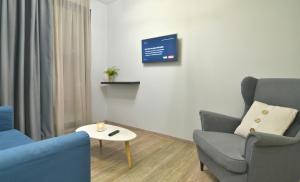a living room with two chairs and a table and a tv at Feel Athens Studios at Monastiraki in Athens