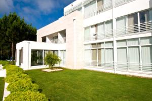 a white building with a lawn in front of it at Lavanda Hotel Miravillas in Praia de Mira
