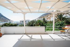 - une terrasse blanche avec un mur blanc, une table et des chaises dans l'établissement Oasis, à Kamarai