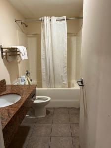a bathroom with a tub and a toilet and a sink at Metro Inn & Suites in Jacksonville +17 photos