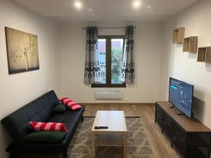 a living room with a black couch and a tv at Magnifique appartement de 60m2 in Le Blanc-Mesnil