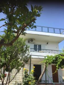 un edificio bianco con balcone e alcuni alberi di Mavro lithari Summer Home ad Anávissos