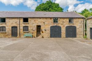 een oud stenen gebouw met twee garagedeuren en een bank bij The Hayloft in Mold