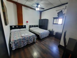 two beds in a room with wooden floors at Hotel Garcias Suites, Linares in Linares