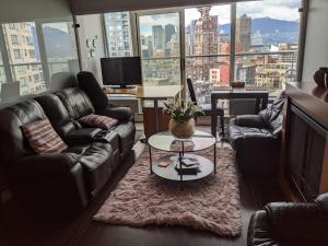 a living room with couches and a table and a large window at Vancouver Downtown Accommodation in Vancouver