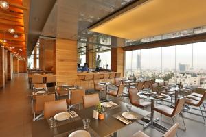 a restaurant with tables and chairs and large windows at AlQasr Metropole Hotel in Amman