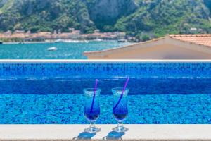 twee blauwe glazen naast een zwembad bij Apartments Dončić in Kotor