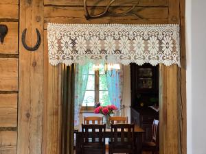 a dining room with a table and a curtain at Koronkowa Chata in Michalin