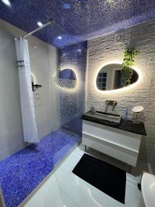 a bathroom with a sink and a shower with blue tiles at Pink Tropical Champagne in Reims +59 photos