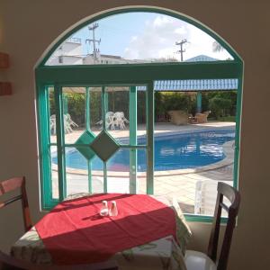 a room with a table and a window with a pool at Pousada Marahú in Porto De Galinhas