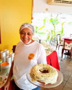 a woman holding a plate with a cake on it at Pousada Marahú in Porto De Galinhas