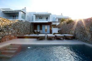 a house with a swimming pool and a stone wall at Villa ANASA private Pool & Jacuzzi 8pax at Panormos in Panormos Mykonos